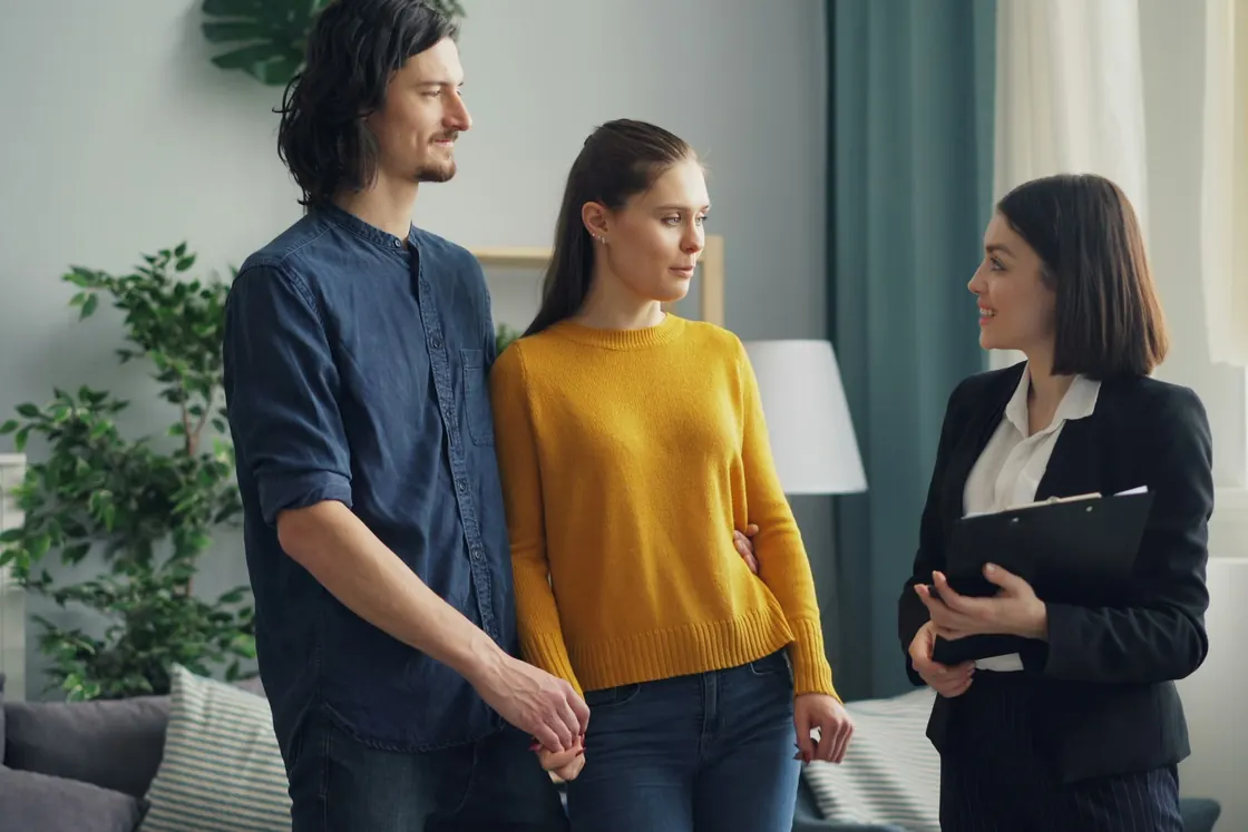 An adviser with a folder talking with a couple in their living room